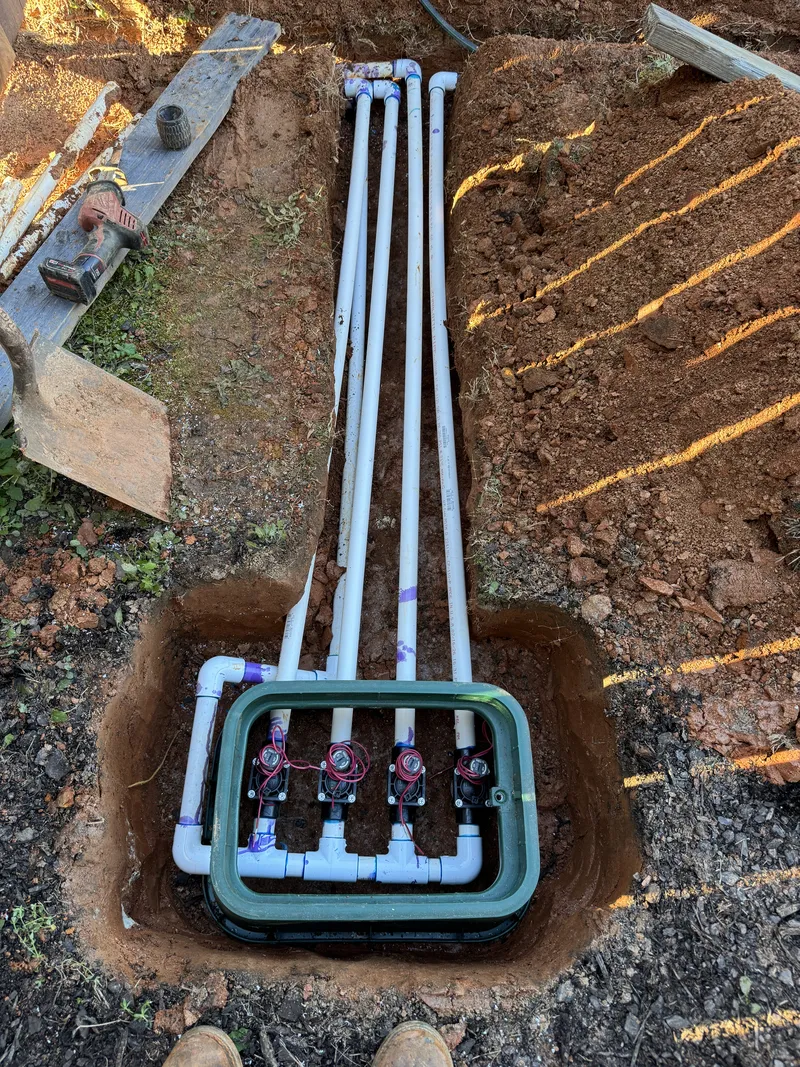 New irrigation valve box with manifold set into a dug hole before backfill